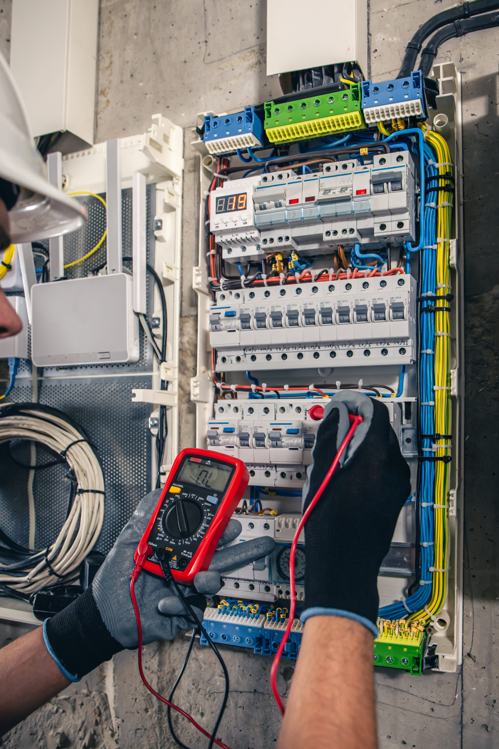 Man, an electrical technician working in a switchboard with fuses. Man, an electrical technician working in a switchboard with fuses. Installation and connection of electrical equipment. Professional uses a tablet.